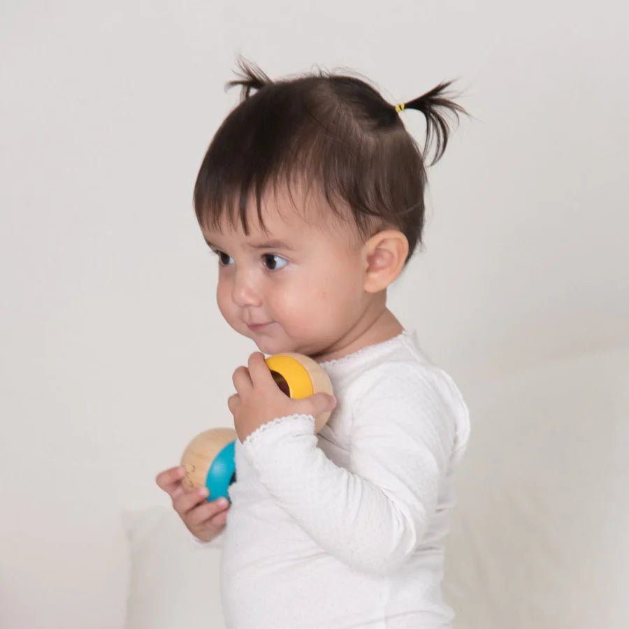 Child holding two colorful sensory toys against a plain background