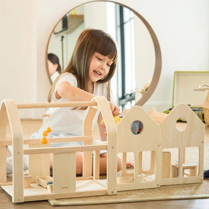 Child playing with a wooden dollhouse in a home setting
