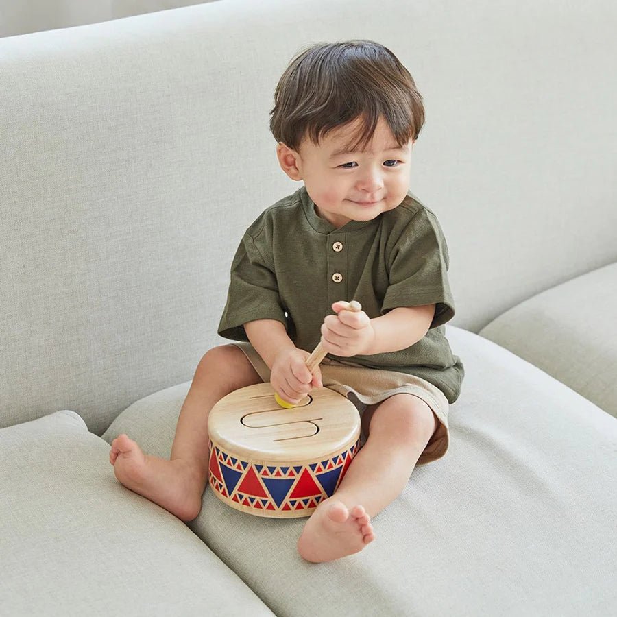 Child playing with a colorful drum on a light-colored couch