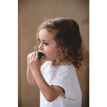 Child holding a blue wooden whale whistle on a neutral background