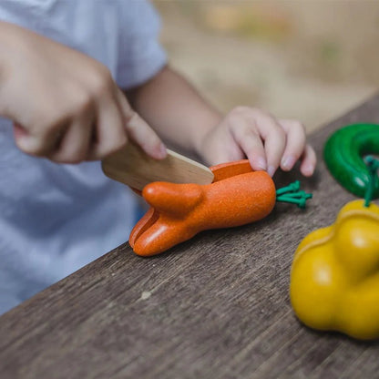 Child playing with toy vegetables on a wooden surface
