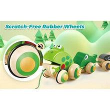 A green frog-shaped wooden toy car with rubber wheels, shown on a soft pastel background with the text 'Scratch-Free Rubber Wheels' and a circular inset close-up of the wheel detail.