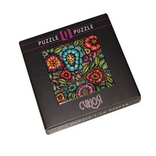 Jigsaw puzzle box with colorful floral design and 'Curiosi' branding on a white background