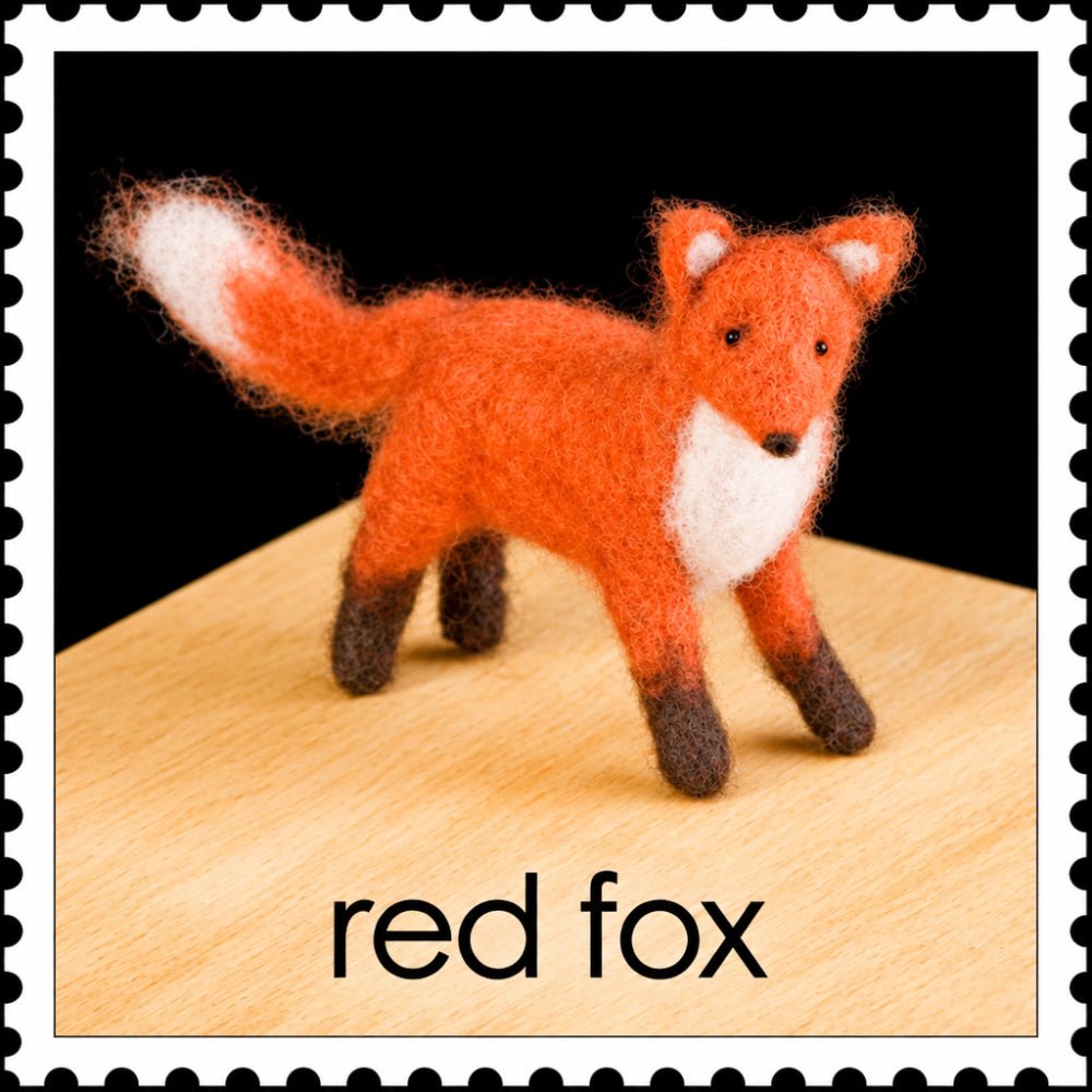 Felted red fox on a wooden surface against a black background