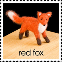 Felted red fox on a wooden surface against a black background