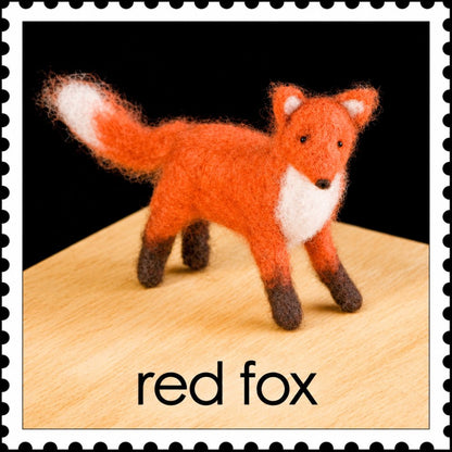 Felted red fox on a wooden surface against a black background