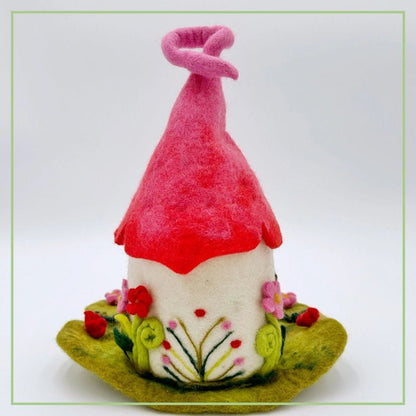 Back side of felted fairy house with red roof on a white background