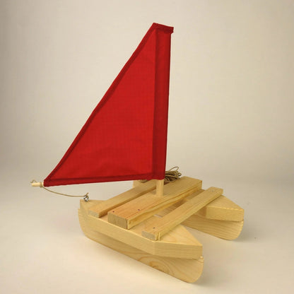 Wooden toy sailboat with a red sail on a beige background