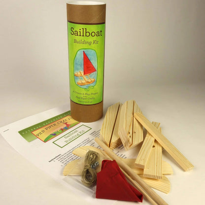 Sailboat building kit with wooden sticks, a red sail, and a cylindrical container labeled 'Sailboat Building Kit' on a white background.