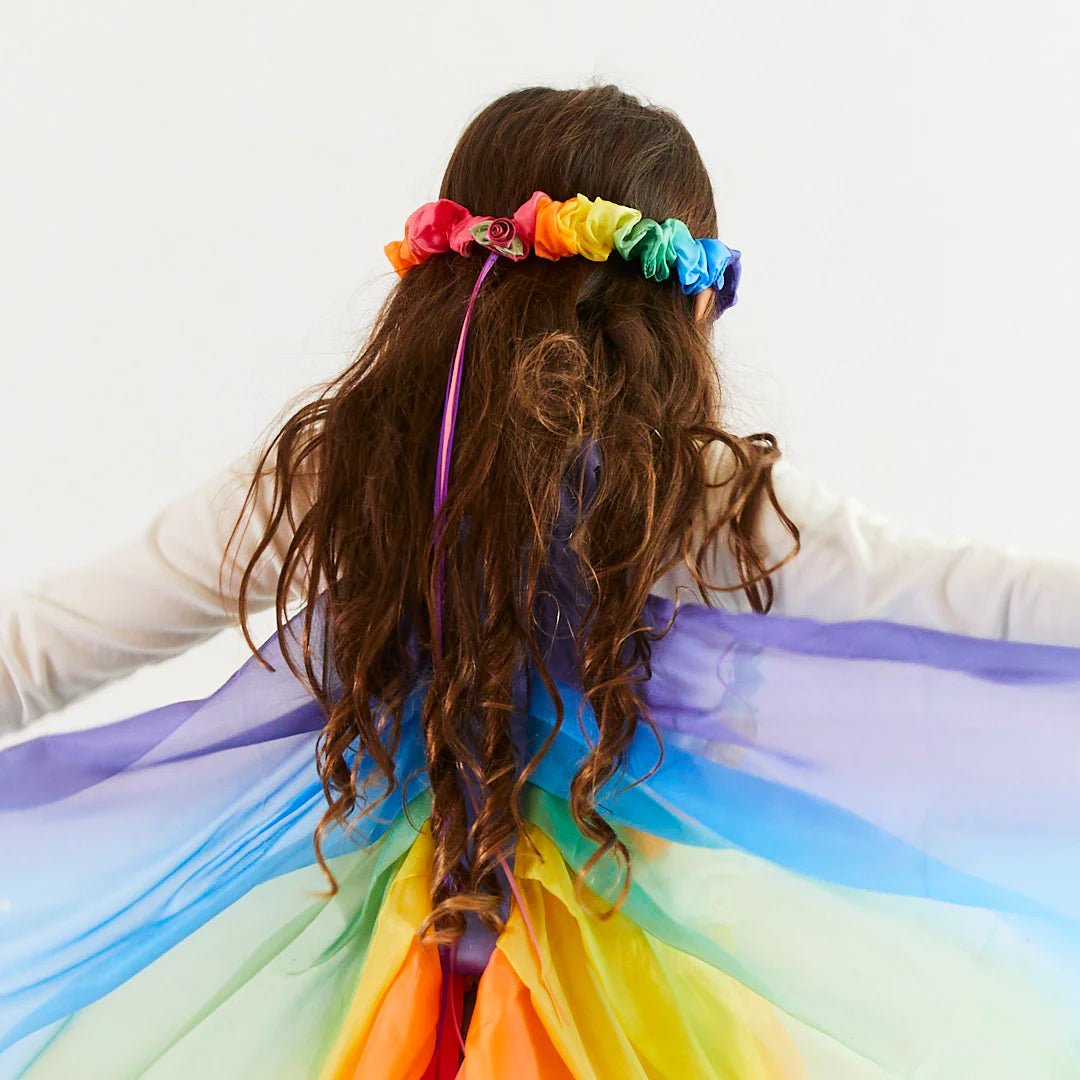Child wearing silk rainbow garland and rainbow wings