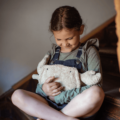 Young girl holding a plush crab on a wooden floor