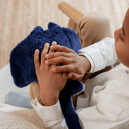 Top down view of a child sitting in a chair holding a manta ray stuffed animal on a blurred background