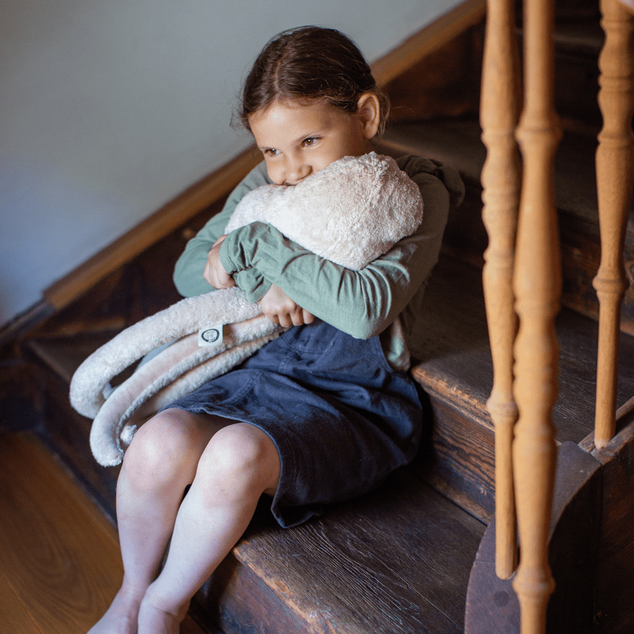 Child sitting on a staircase holding a plush octopus toy