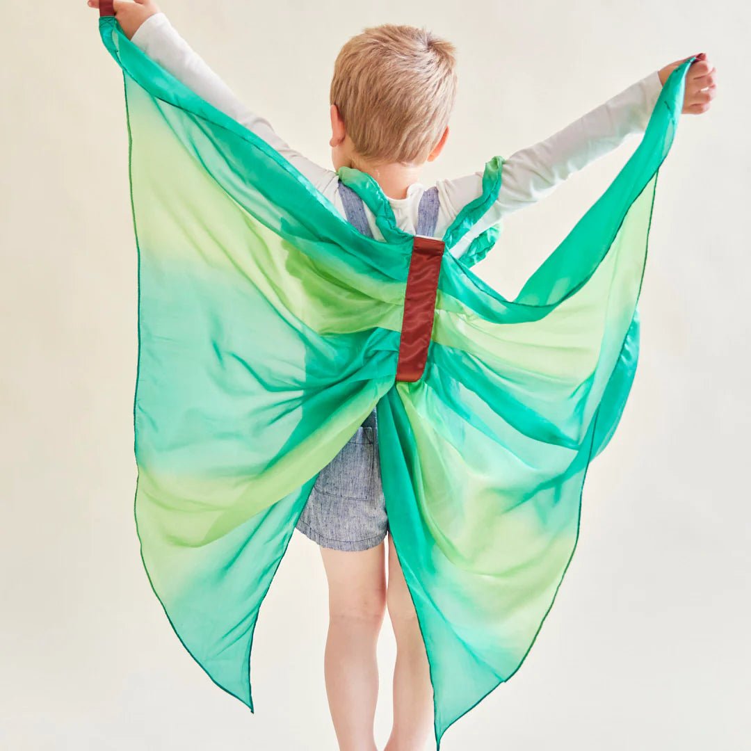 Child with back turned wearing green silk fairy wings