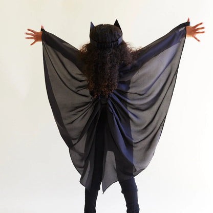 Child facing away from the camera, wearing black silk wings and a black bat ear headband