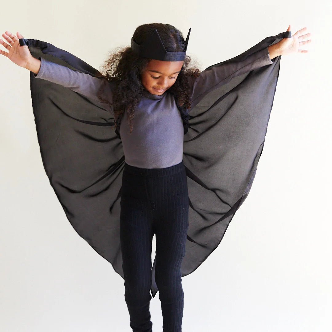 Child wearing black silk wings and a black bat ear headband