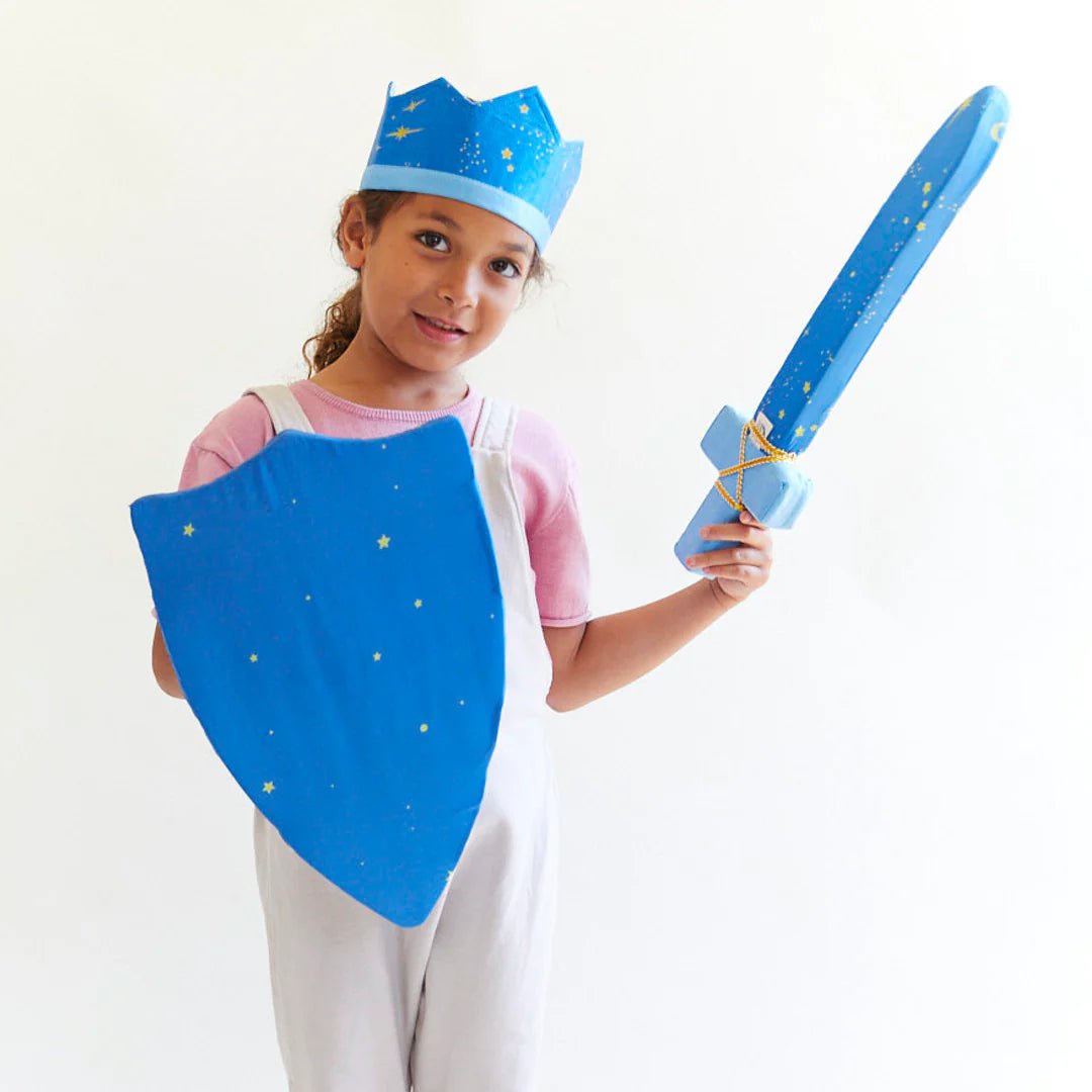 Child wearing a blue crown with yellow stars, holding a silk sword and shield with the same pattern