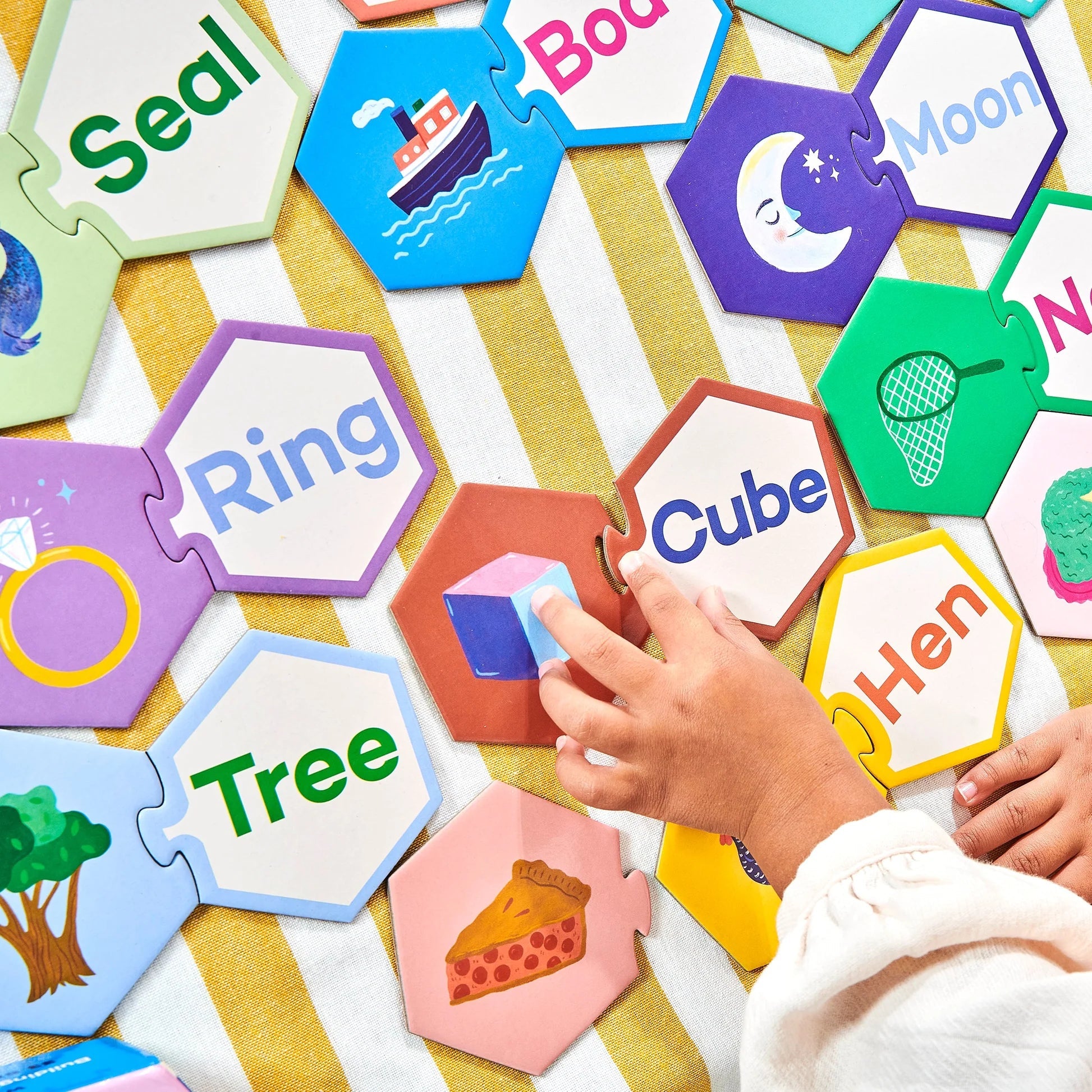 Children's educational puzzle with colorful hexagonal cards on a yellow and white striped surface