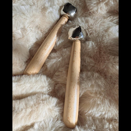 Two bells on wooden handles on a fluffy beige background