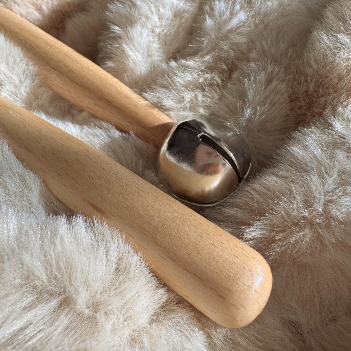 Wooden tool with a metal bell on a fluffy white surface