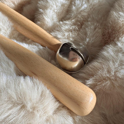 Wooden tool with a metal bell on a fluffy white surface