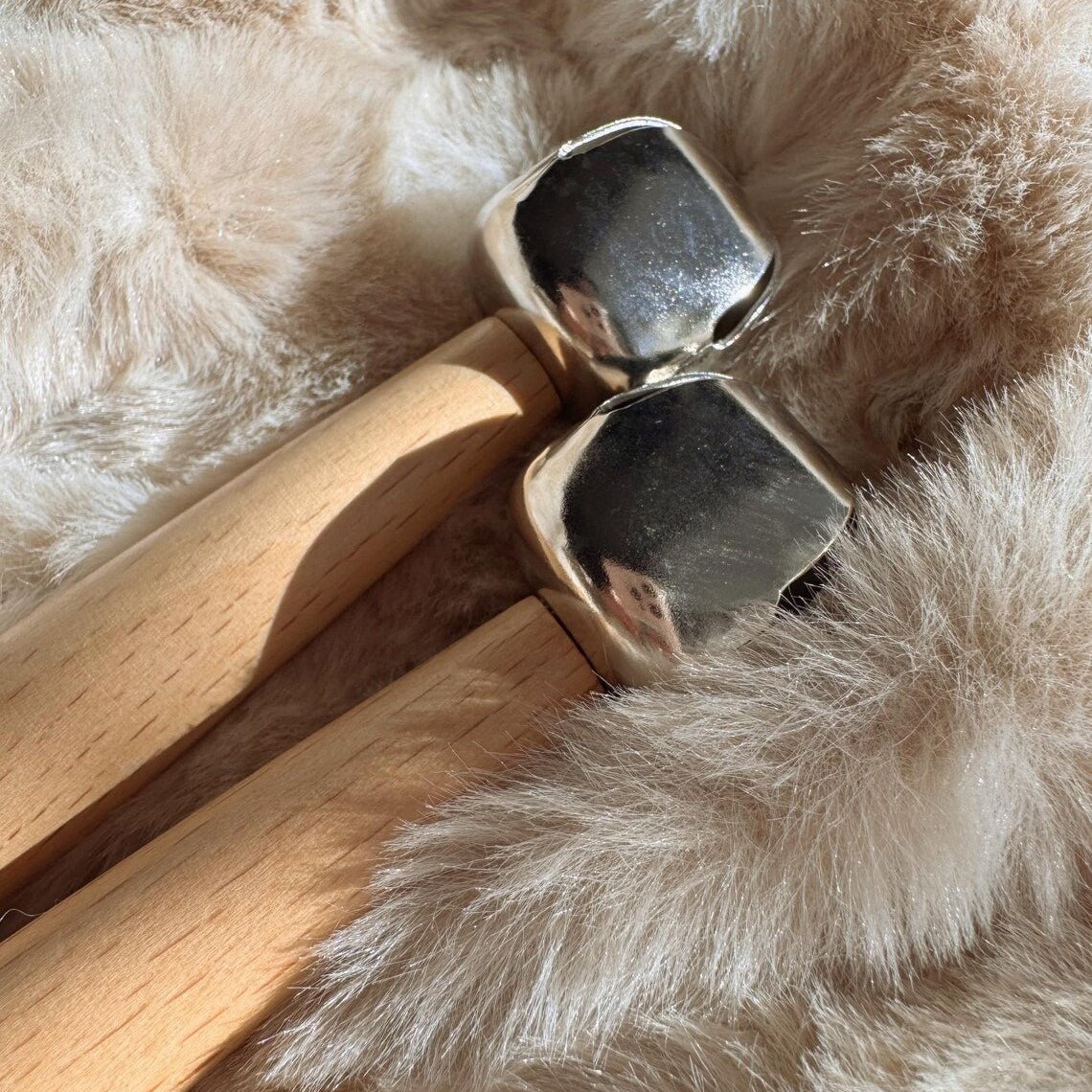 Set of two single bells on a wooden handle on a beige background