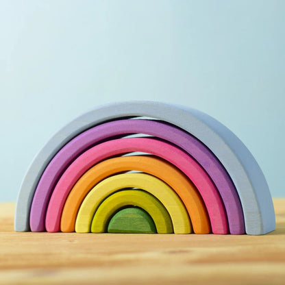 Stackable rainbow arcs on a wooden surface on a light blue background