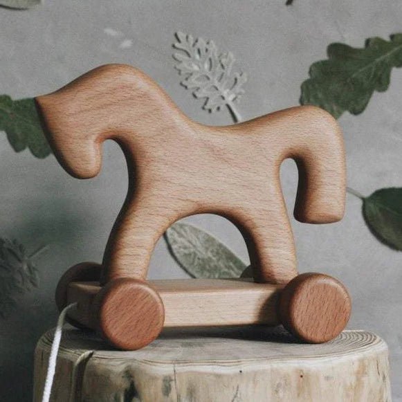 Wooden horse pull toy on a rustic wooden block with a natural background
