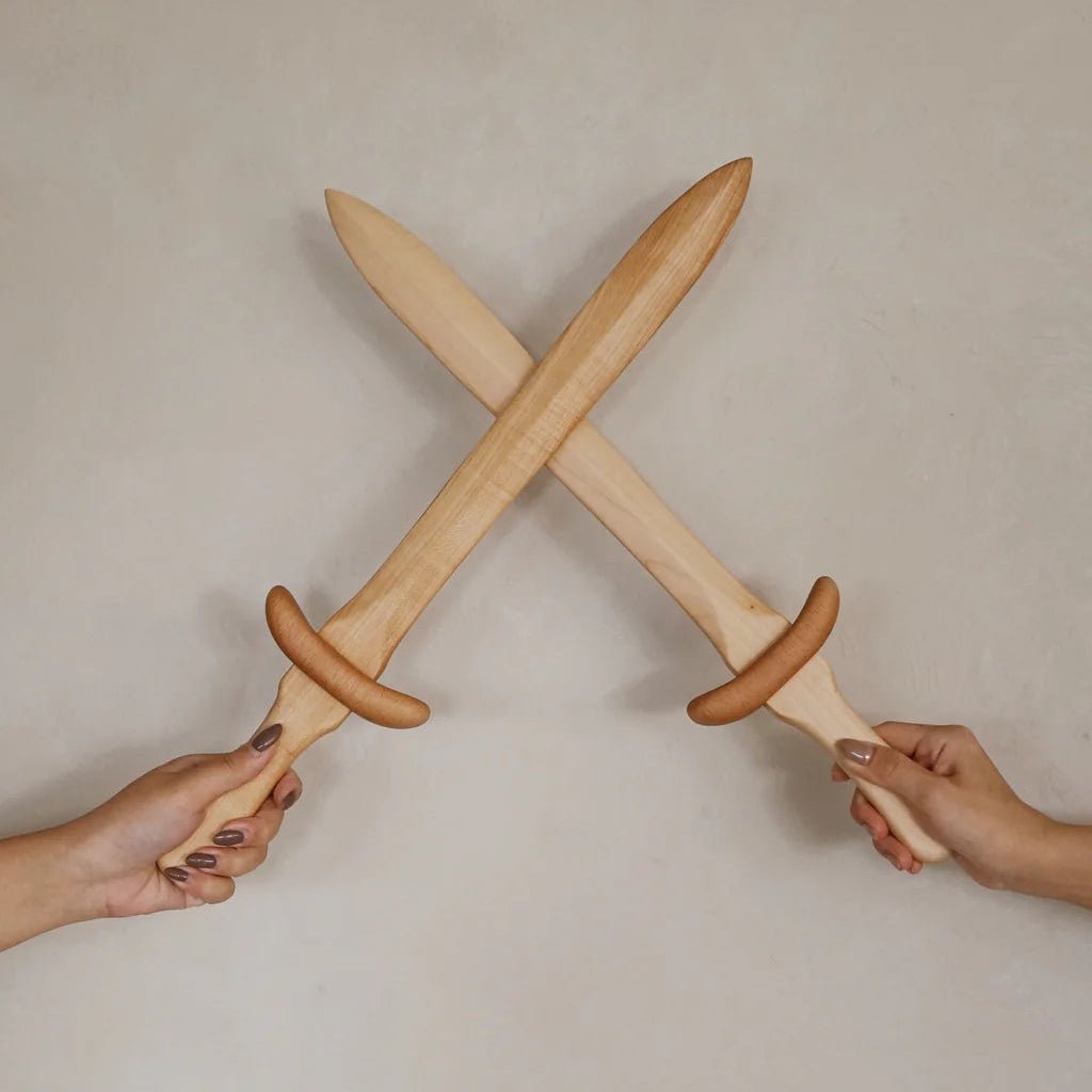 Two hands holding crossed wooden swords against a plain background