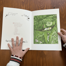 Open book with text on the left and an image of a young girl sleeping in the forest on a wood background