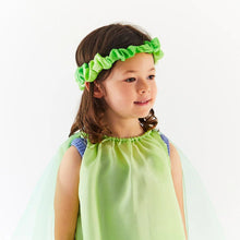 Child wearing a green dress and headband against a white background