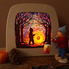 A vintage-style television-shaped light box displaying a colorful forest scene with a silhouette of a child holding a flashlight, casting a glowing lantern. The scene is styled with autumn props including a pinecone, a small felt gnome, and a pumpkin on a dark surface.
