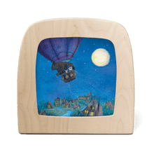A gnome and other creatures fly above a dimly lit city in a hot air balloon at night time