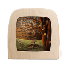 Squirrel reading a book in a large tree with fresh blossoms, while fairies flit around the green meadow