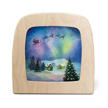 Toverlux lamp featuring a painted winter scene with snow-covered cabins, evergreen trees, Santa's sleigh, and colorful aurora lights in the night sky.