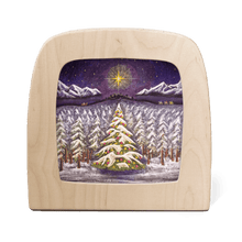 Wooden frame with silhouette of a winter landscape, featuring a large Christmas tree in the foreground and the journey to Bethlehem in the background