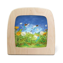 Wooden frame with silhouette of fairies flying around a field of dandelions