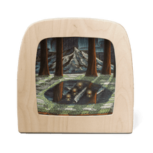 Wooden frame with silhouette of a moonlit forest with melting snow and a mountain landscape and aurora borealis in the background
