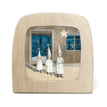 Silhouette of three children in white outfits and hats holding stars, set against a window view of trees.