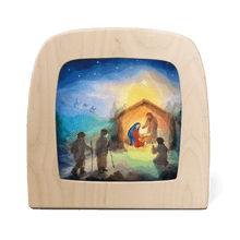 Wooden frame with a silhouette of a Nativity scene featuring Mary, Joseph, baby Jesus, the three wise men, and others gathered around the manger