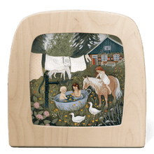 Silhouette of two children in a wash tub outside, with horses, laundry, and a house in the background