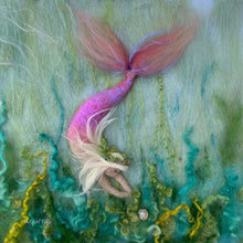 Mermaid with a pink tail lying among underwater plants