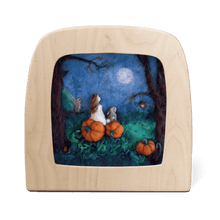 Silhouette of a girl and a rabbit sitting on pumpkins looking at the moon