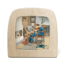 A mother and children sit in front of the fireplace reading books