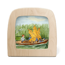 Wooden frame with a painted scene of children in a boat with a leaf sail on a white background