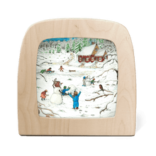 Silhouette of children playing in the snow with a red cottage in the background