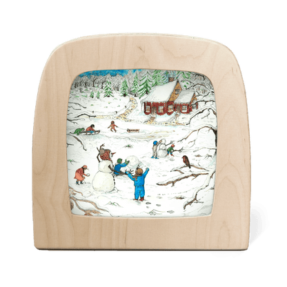 Silhouette of children playing in the snow with a red cottage in the background