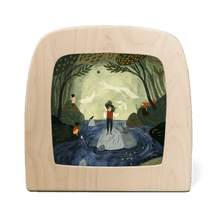 Wooden frame with a painted scene of a person standing on a rock in a forest.