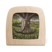 A gnome stands outside of a large tree that has been converted into a home with illuminated lights, in the middle of a field