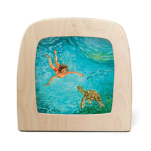 Silhouette featuring a child swimming in the ocean with a sea turtle.